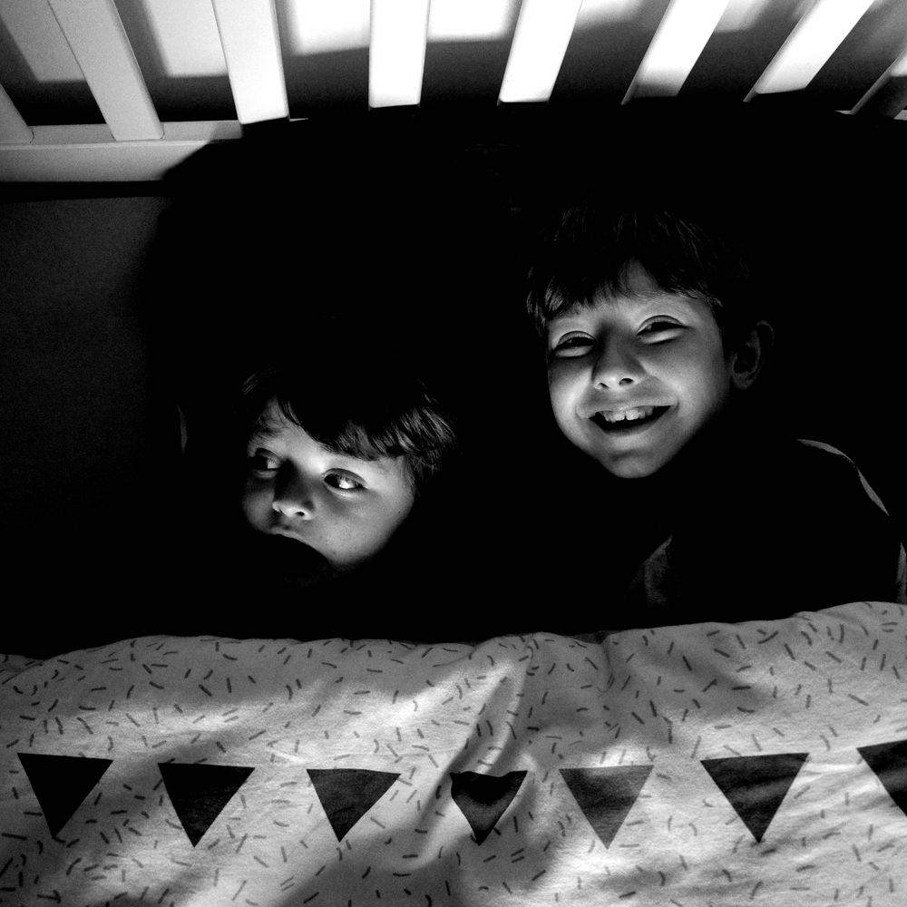 Two boys smiling in bed.