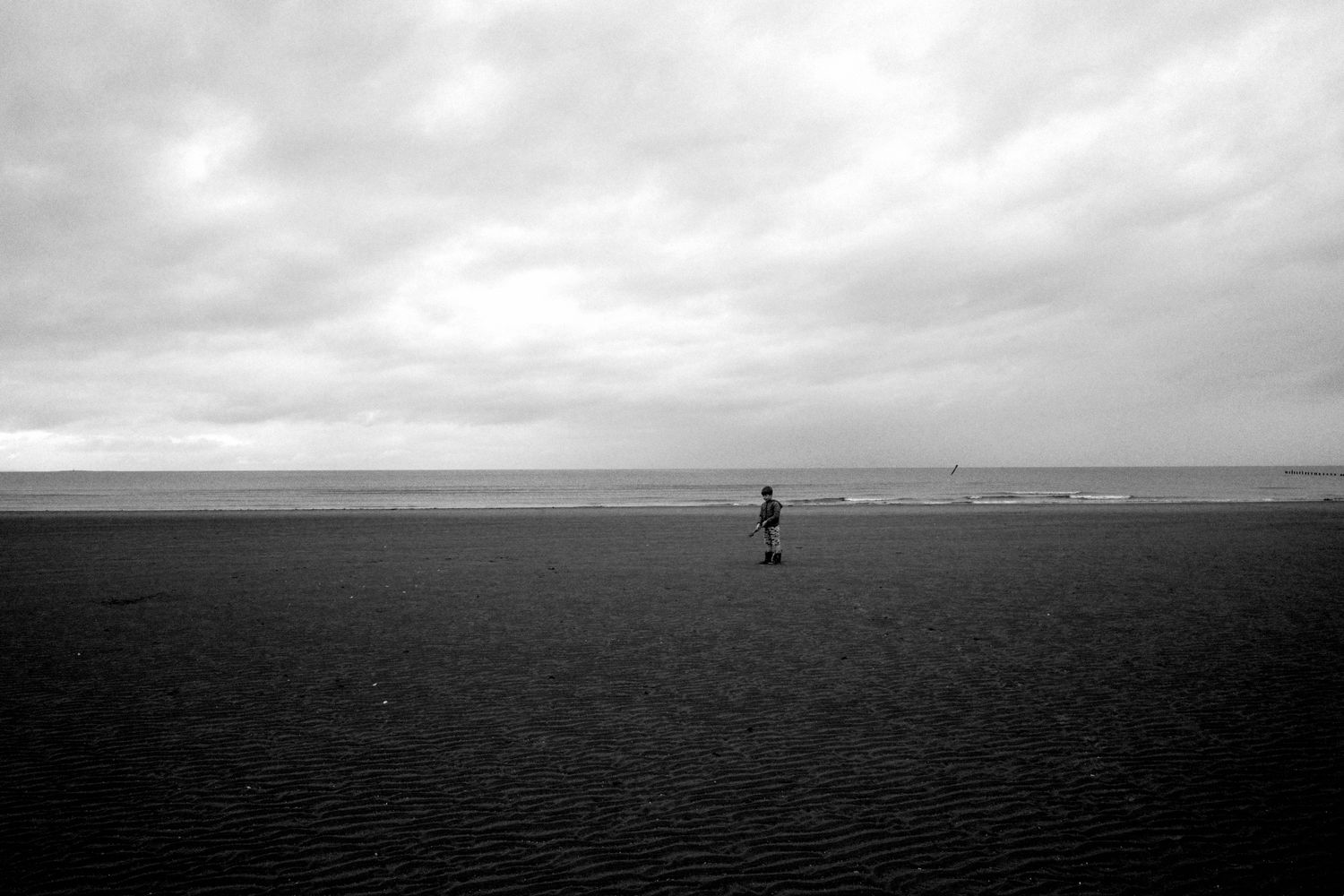 A boy standing on the beach in front of the sea