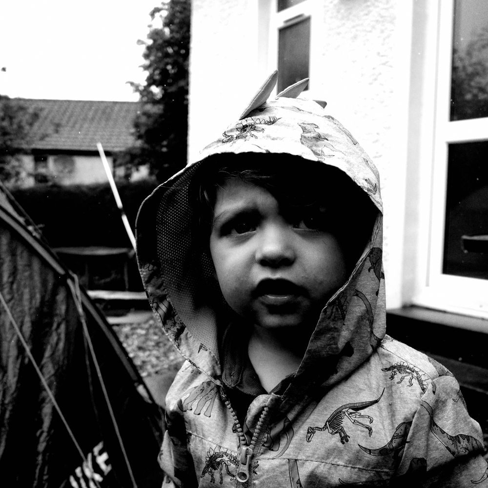 Faser, 2 years old with a hood up in the garden