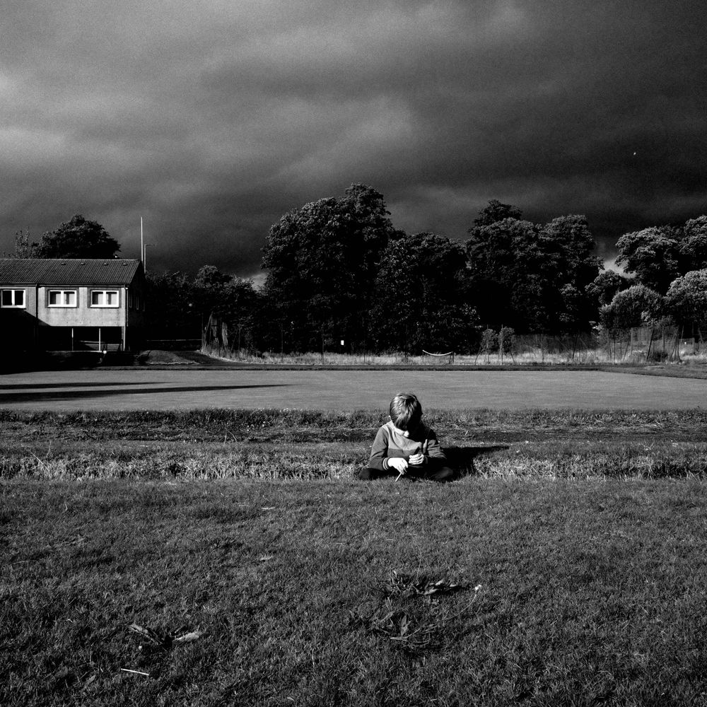 Boy sitting with dark clouds behind him
