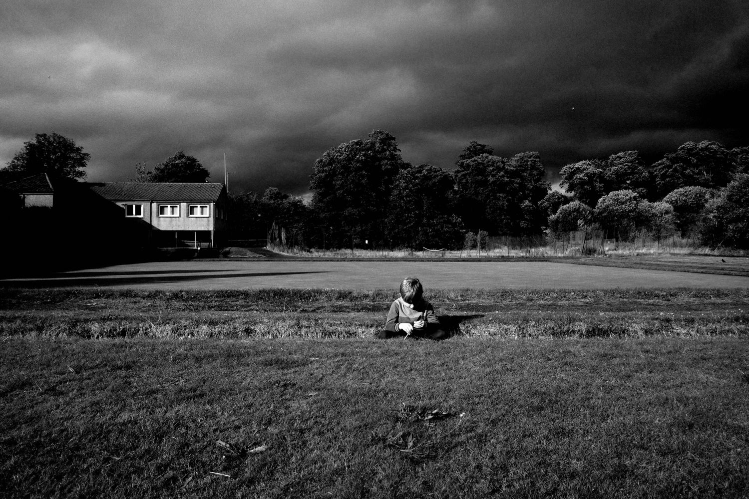 Boy sitting with dark clouds behind him